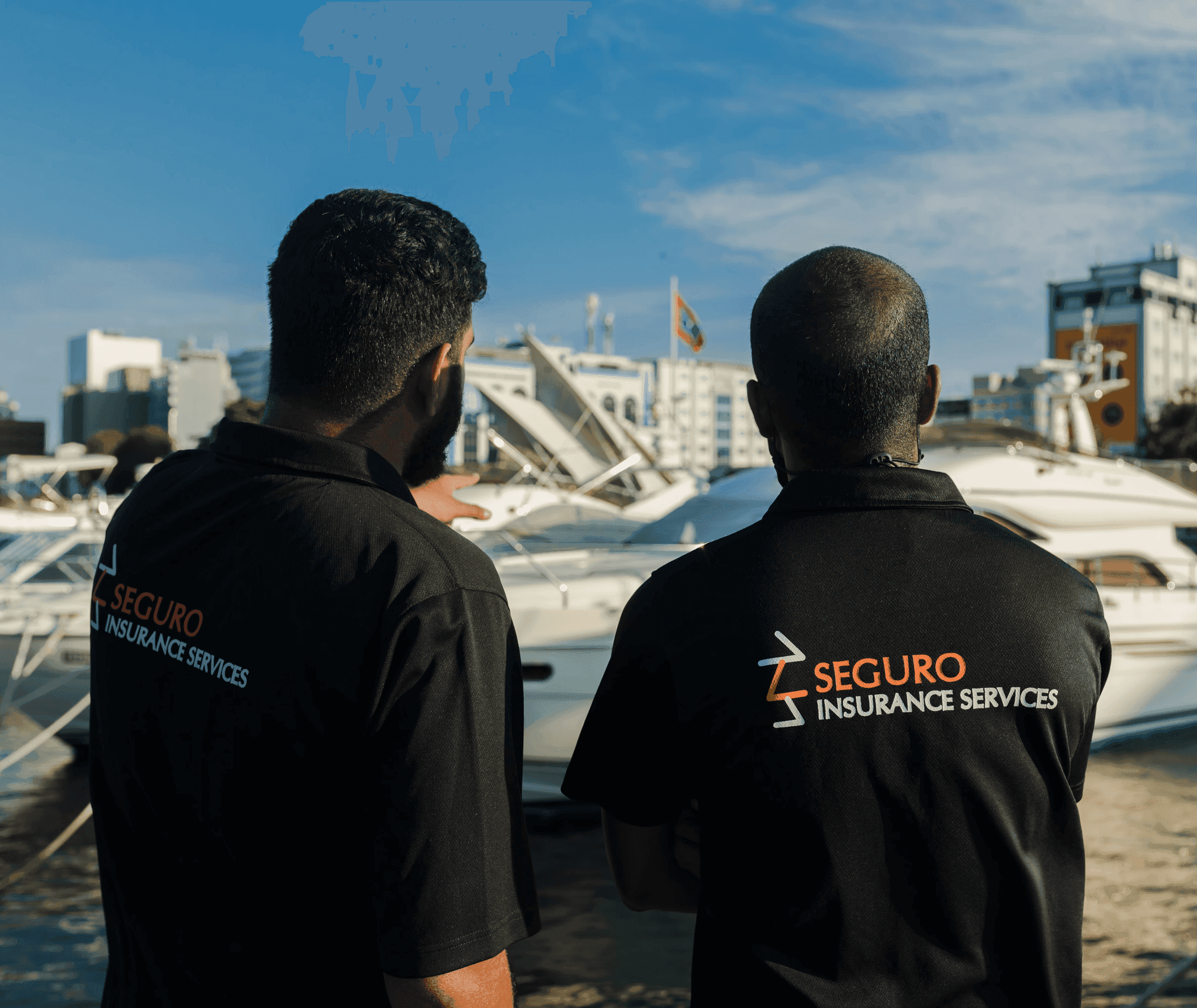 Two Seguro staff in company polo shirts looking out over the harbour
