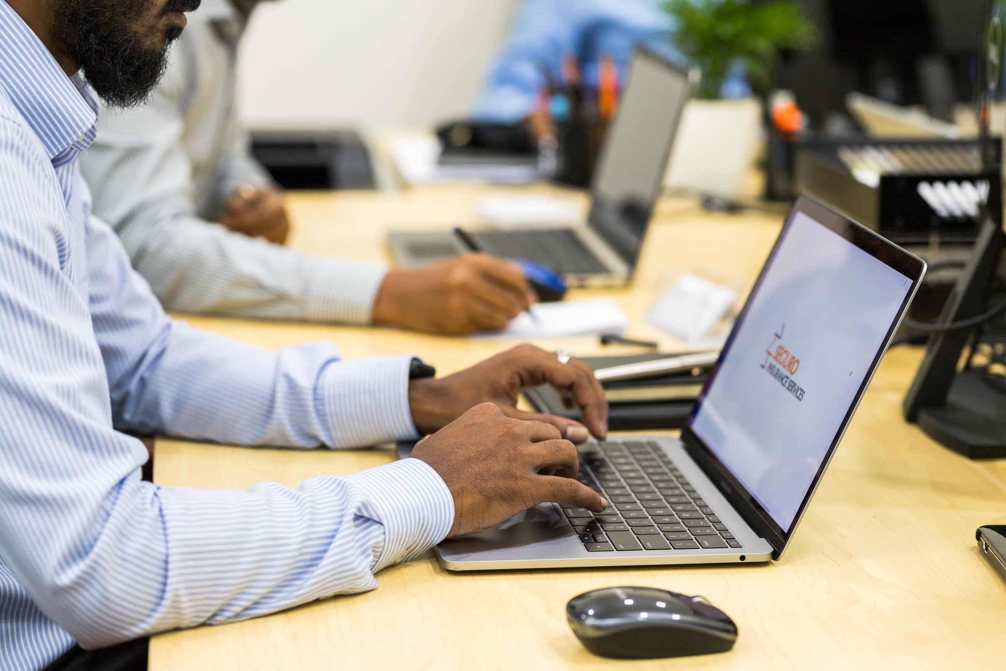 Hands at a laptop and notebook on an office desk